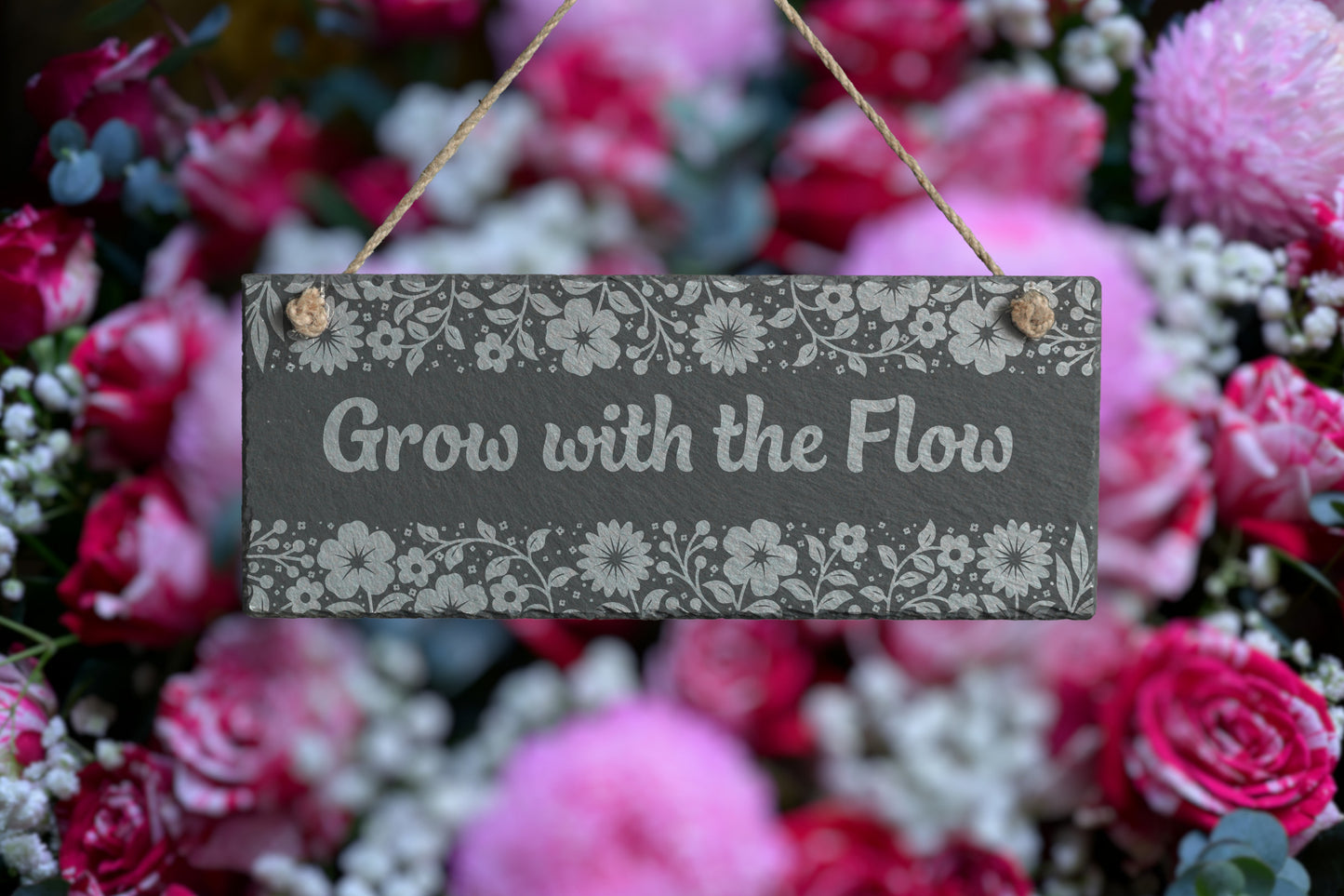Customizable slate sign with engraved floral border and the text 'Grow with the Flow', hanging in a garden setting.